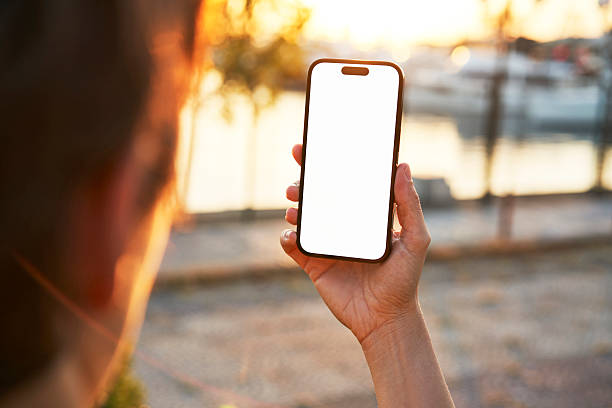 istock Young woman showing mobile phone blank white screen on Marina Background 2218131107