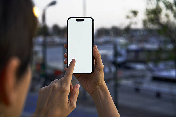 istock Young woman showing mobile phone blank white screen on Marina Background 2218131148