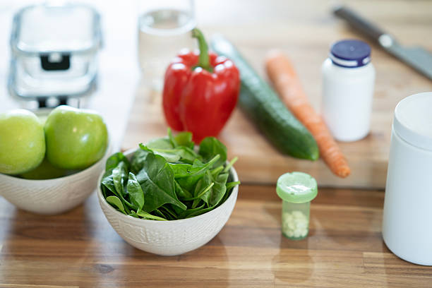 Assorted fresh vegetables, dietary supplements, and nutritious ingredients arranged on a wooden surface, promoting a healthy and balanced lifestyle.