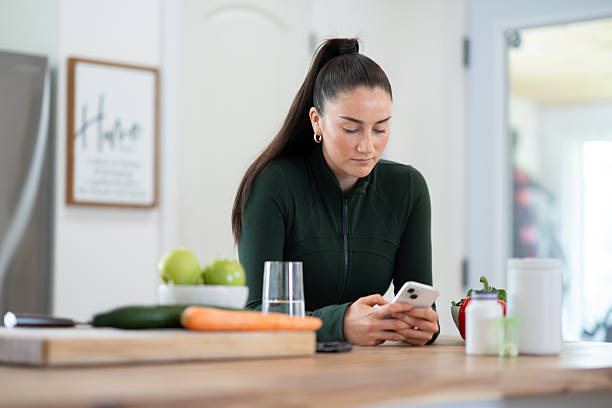 istock Woman in Kitchen Using Smartphone for Research While Preparing Vegetables 2218133859