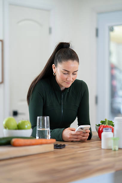 istock Woman Browsing Smartphone in a Modern Kitchen with Fresh Vegetables 2218133876