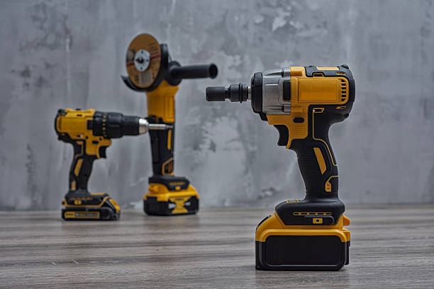 istock Set of cordless power tools, including a drill, impact driver, and grinder on a wooden surface with a concrete wall. Tools for construction or DIY projects. 2218134897