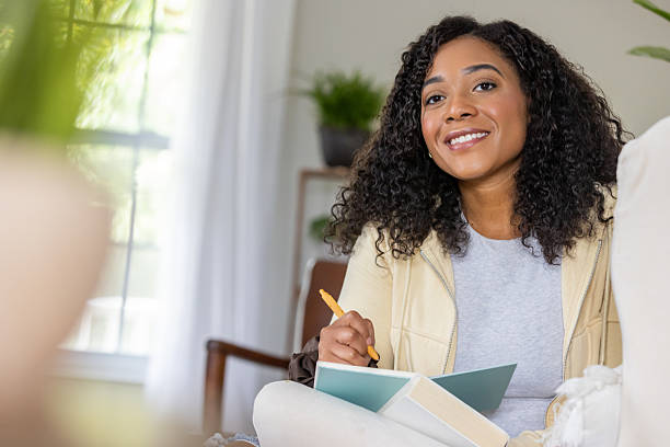 istock Woman records her thoughts and ideas while journaling in diary while spending the day at home 2218144517