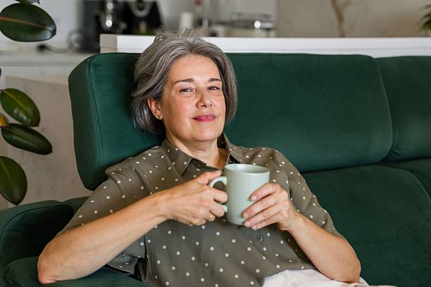 istock Senior woman relaxing on sofa with a mug 2218145021