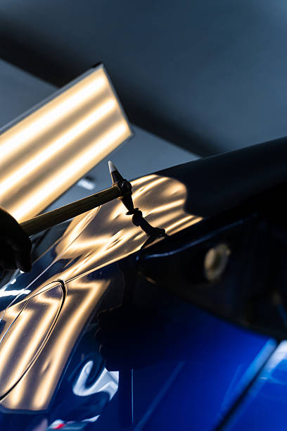 istock Technician uses PDR tools to remove dents from a car hood during paintless dent repair. Paintless dent repair PDR involves tapping dents under light reflection for precision. 2218145187