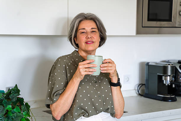 istock mature woman holding a mug in her modern kitchen 2218145233