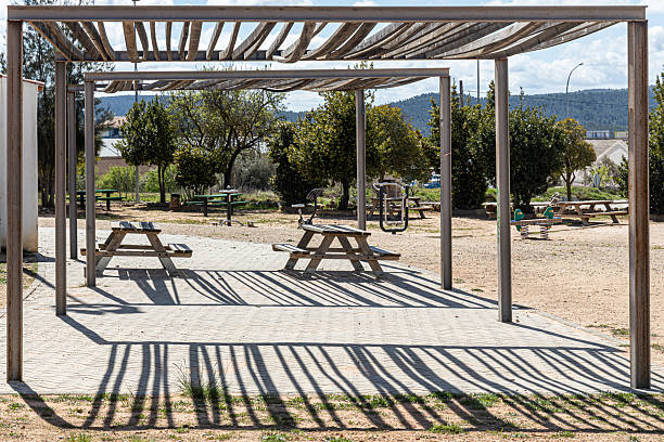 istock Two Empty gray wooden tables on the green plants background with a pergola 2218145467