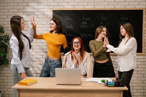 Teacher surrounded by students having a lively discussion in a classroom setting, engaging with a chalkboard.