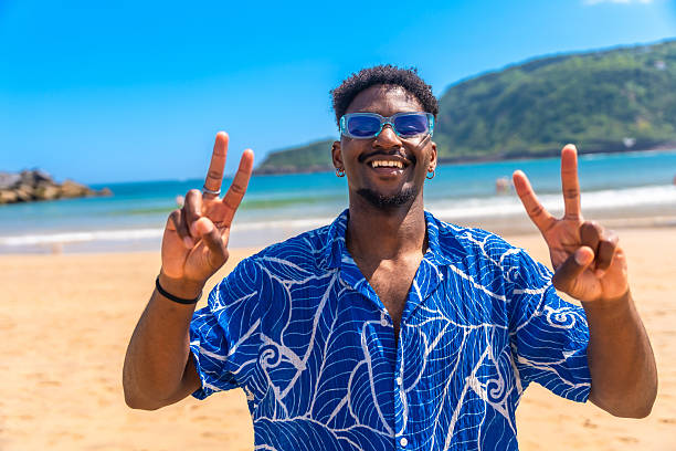 istock Young man making peace sign on a sunny beach 2218150649