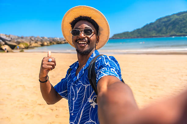 istock Young man taking a selfie on a sunny beach giving thumbs up 2218150655