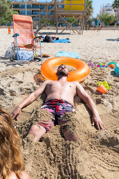 istock Young man relaxing buried in the sand at the beach 2218151990