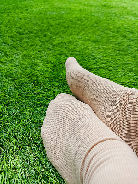 istock Brown sock template on female leg, isolated on green grass background. 2218152201