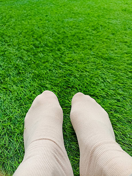 istock Brown sock template on female leg, isolated on green grass background. 2218152203