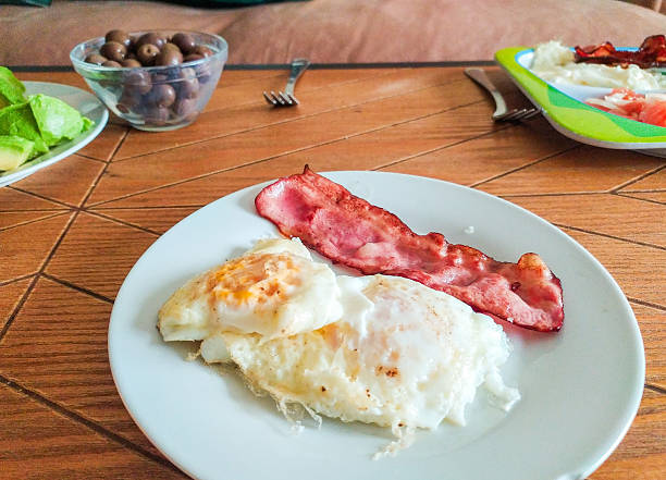 Fried eggs with bacon on a blue background close-up