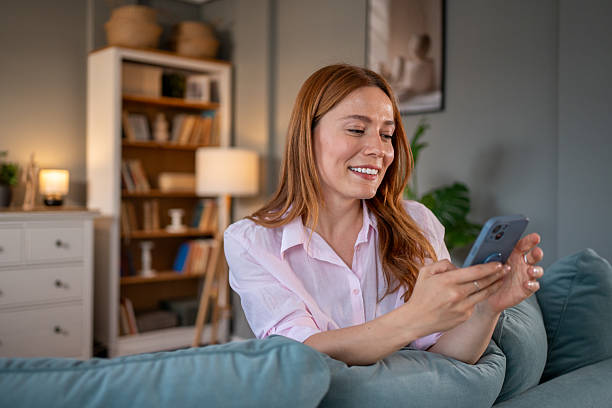 istock Smiling woman using smartphone on sofa at home 2218171844