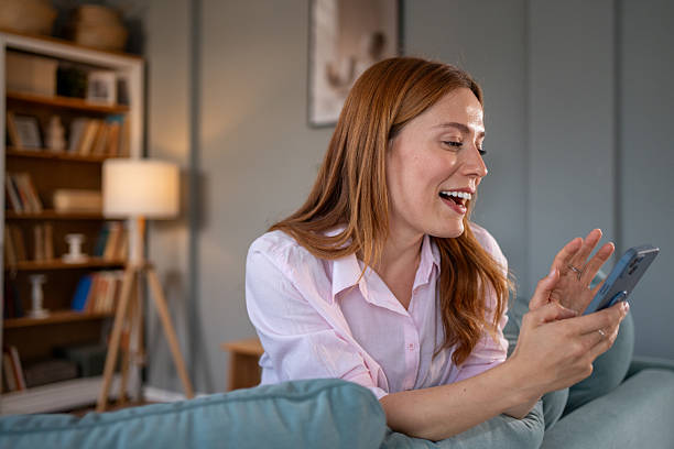 istock Happy woman video calling with smartphone on sofa at home 2218171852
