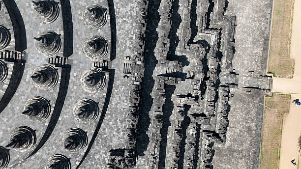 A close-up view of ancient stone stupas at a temple complex, featuring intricate designs and a cloudy sky in the background