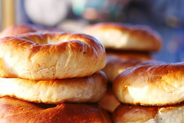 Warm, golden bagels stacked high at a bustling bakery in the morning.
