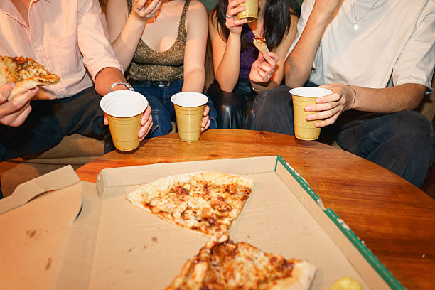 istock Young adults eating pizza and drinking at a house party 2218183255