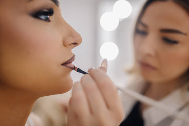 istock Makeup artist applying lipstick on model lips in beauty salon 2218184414