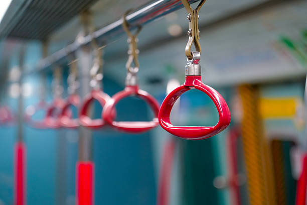 Individual red plastic handles on metal handrails inside the train.