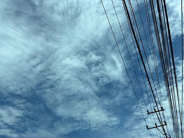 istock Cloudy Blue Sky with Power Lines Crossing Diagonally 2218188612