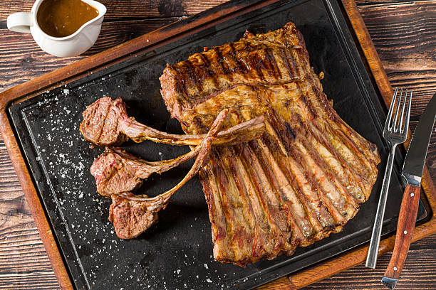 istock Lamb racks grilled with herbs and sauce on a stone board 2218194709