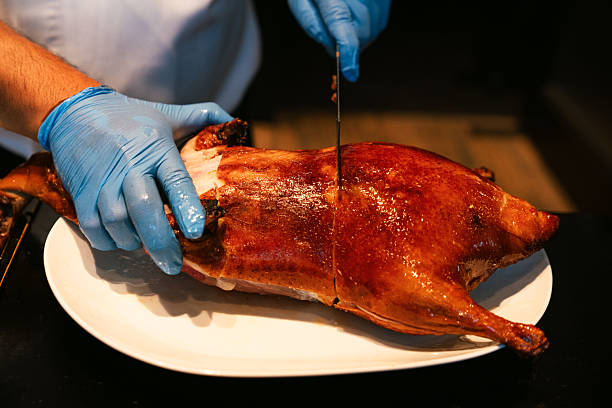 istock Chef Slicing Whole Roasted Peking Duck on Plate 2218197038