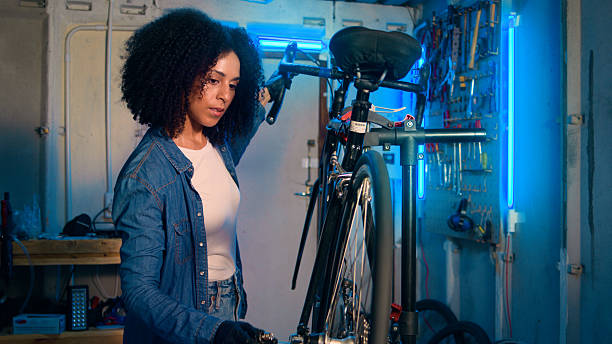 istock Young Woman Repairing a Bicycle in a Brightly Lit Workshop Utilizing Specialized Tools 2218198875