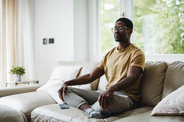 istock Black Man Meditating at Home on Couch 2218200239