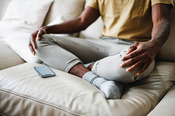 Black Man Relaxing at Home with Phone on Sofa