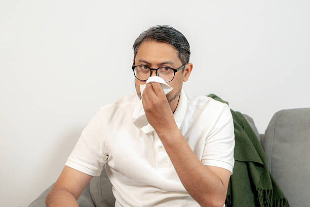 istock Sick man sneezing into a tissue  symptoms of cold, flu, or allergies 2218200390
