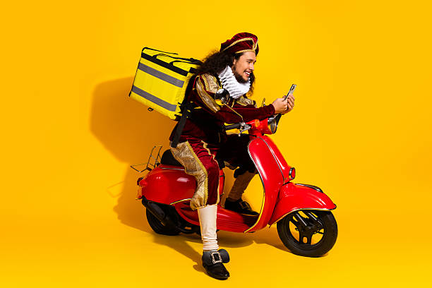 istock A young man in a medieval costume riding a red scooter with a yellow background 2218202872