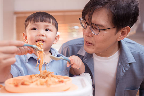 Happy Asian boy enjoying mealtime in the kitchen