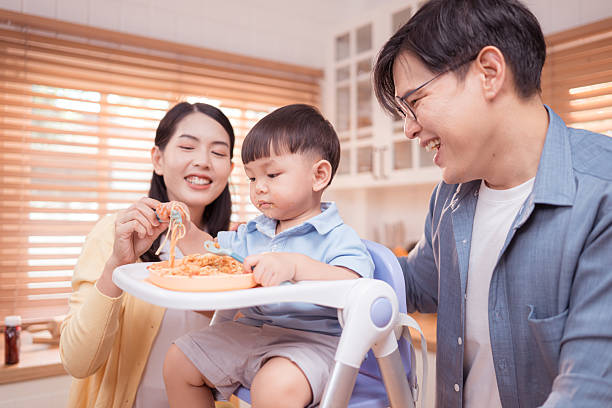 Happy Asian boy enjoying mealtime in the kitchen