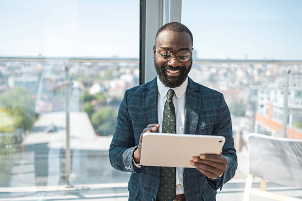 istock Smiling businessman using tablet in modern sunny office with city view 2218206791
