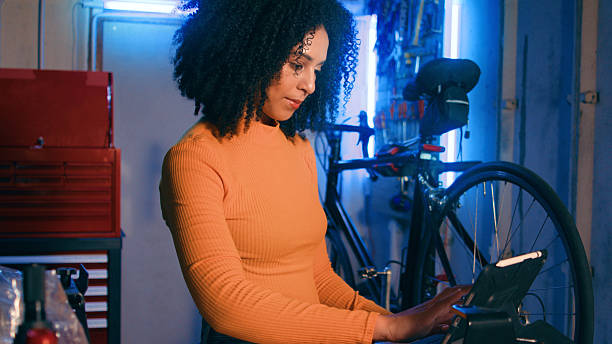 istock Young Woman Mechanic Working on Bicycle in Workshop with Modern Equipment 2218207497