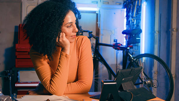 Contemplative Woman at Workstation With a Bicycle Background in a Cozy Workshop