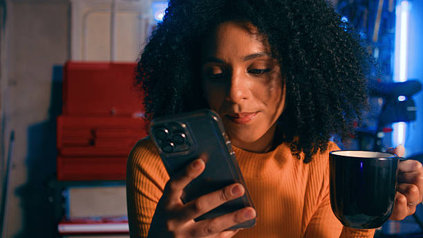istock Young Woman Enjoying Coffee While Using Her Smartphone in a Modern Workshop Ambiance 2218207524