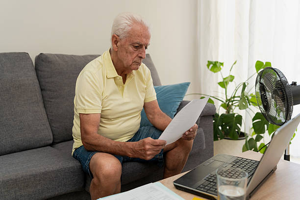 istock Senior man managing home finances using laptop and reading documents on sofa at home 2218211631