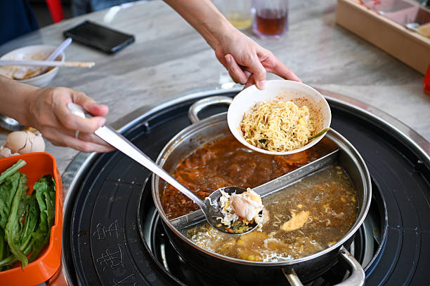Woman picking noodles in Chinese hotpot