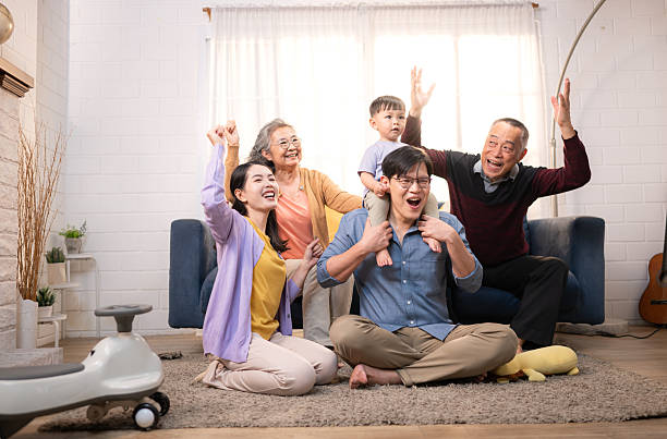 istock Happy multi-generational Asian family enjoying quality time together at home, cheering and smiling with a toddler 2218219829