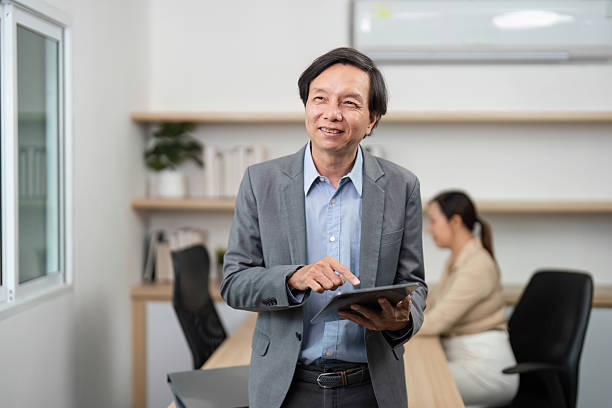 istock Engaged Businessman with Tablet. Professional man smiling while using a tablet in a modern office. 2218219919