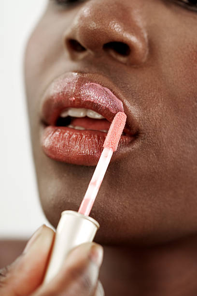 istock Female applying lip gloss indoors during daytime, using a tube with applicator for a glossy finish 2218220555