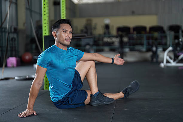 istock Fitness Stretching Routine. A man performing a seated stretch in a gym environment. 2218221080