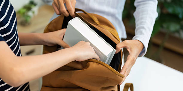 istock Back to School and Organizing Supplies. Two hands placing books into a backpack for school. 2218221574