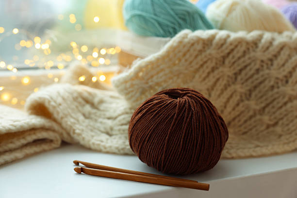 Yarn, crochet hooks and sweater on window sill, closeup