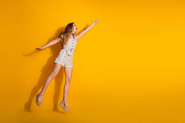 istock Joyful young woman striking a playful pose against a bright yellow background, symbolizing fun, energy, fashion 2218228312
