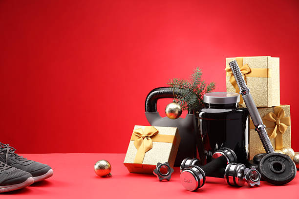istock Dumbbells, kettlebell, container with supplement, sneakers and Christmas decor on red background. Space for text 2218230696