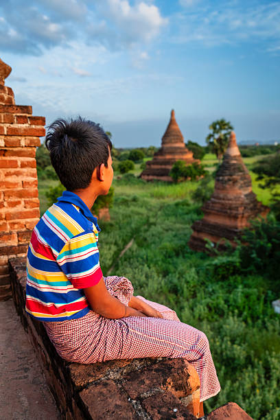 Young Burmese boy with thanaka face paint looking at an ancient temples of Bagan, Myanmar (Burma)